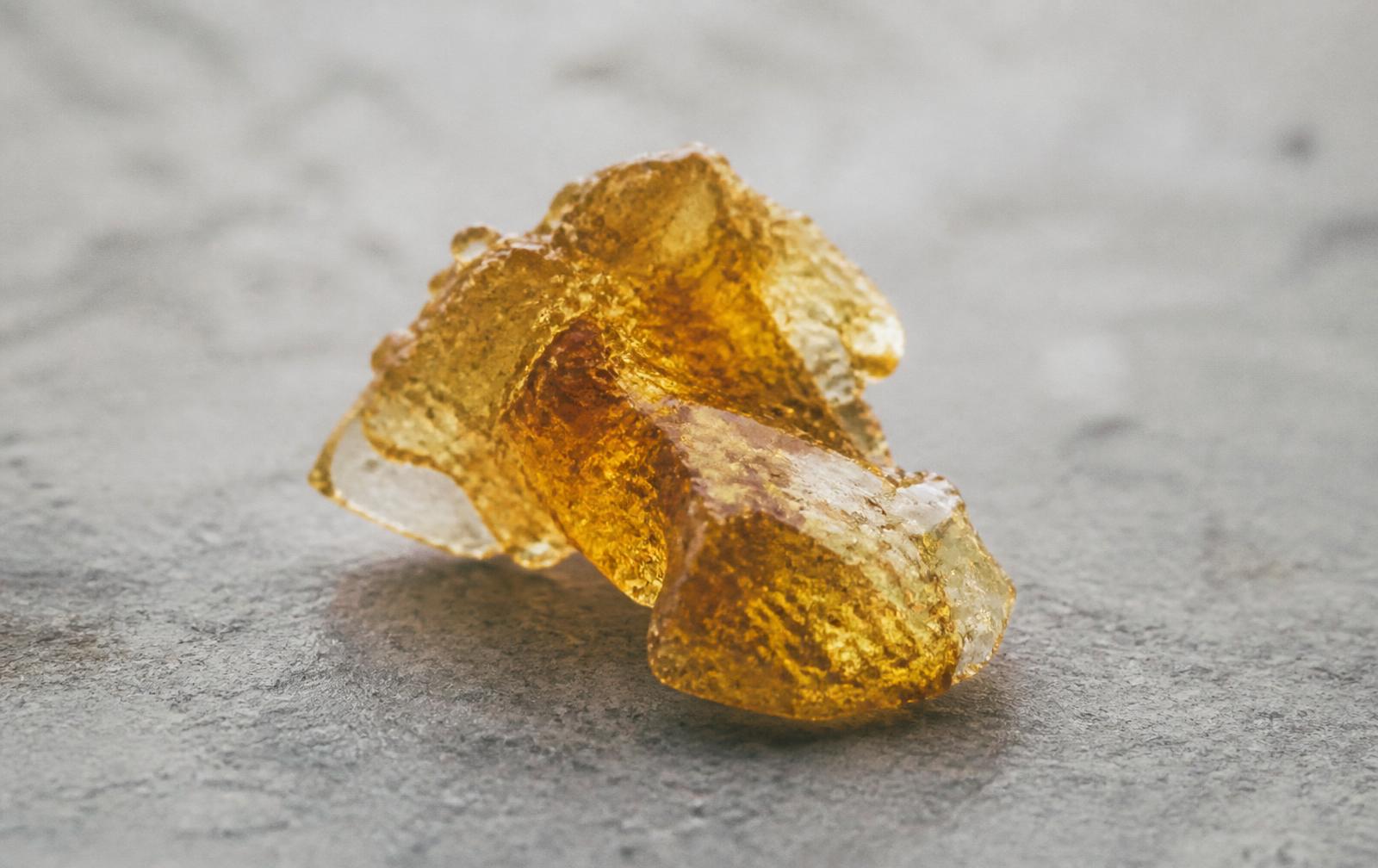 Macro photograph of amber cannabis resin on a pale stone surface